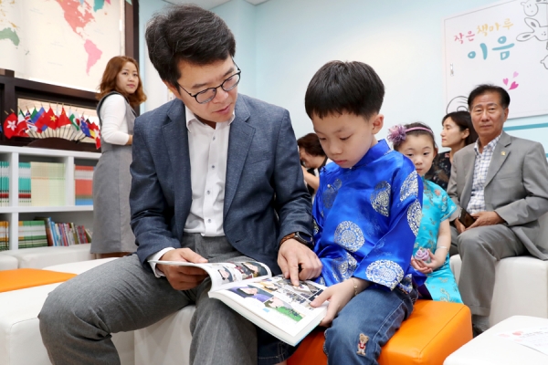정원오 성동구청장과 중국 전통의상 치파오를 입은 어린이가 함께 그림책을 보고 있다.